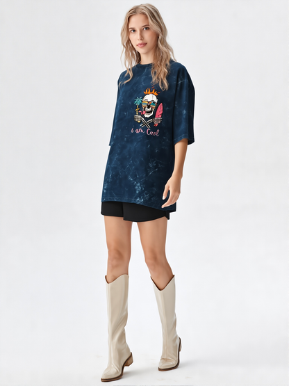 Woman wearing a blue oversized t-shirt with a graphic design and beige knee-high boots on a white background