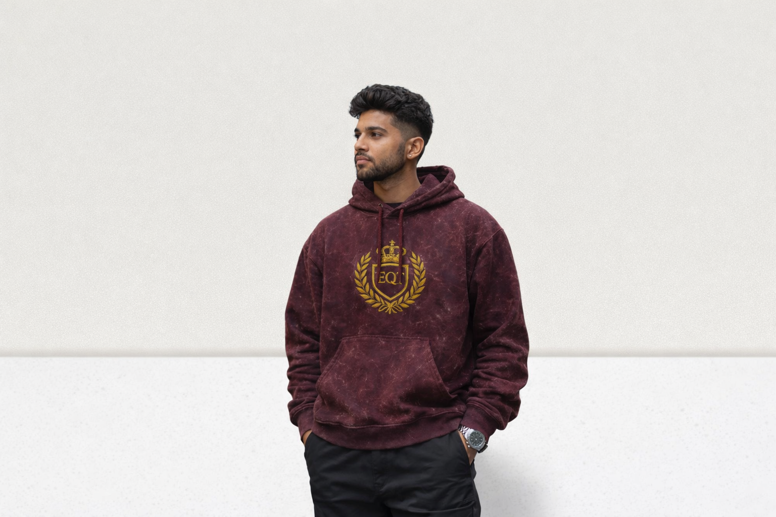 Man wearing a maroon hoodie with a gold emblem on a white background