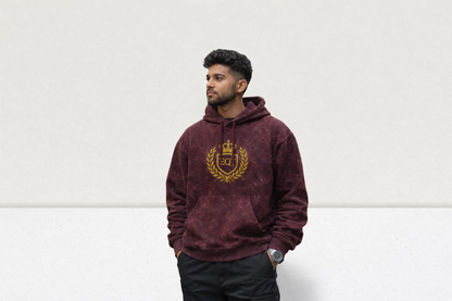Man wearing a maroon hoodie with a gold emblem on a white background