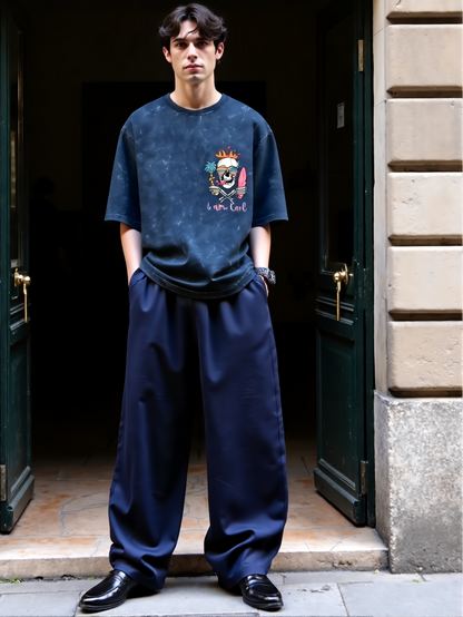 Person wearing a dark blue t-shirt with a graphic design and dark blue pants standing in an archway.