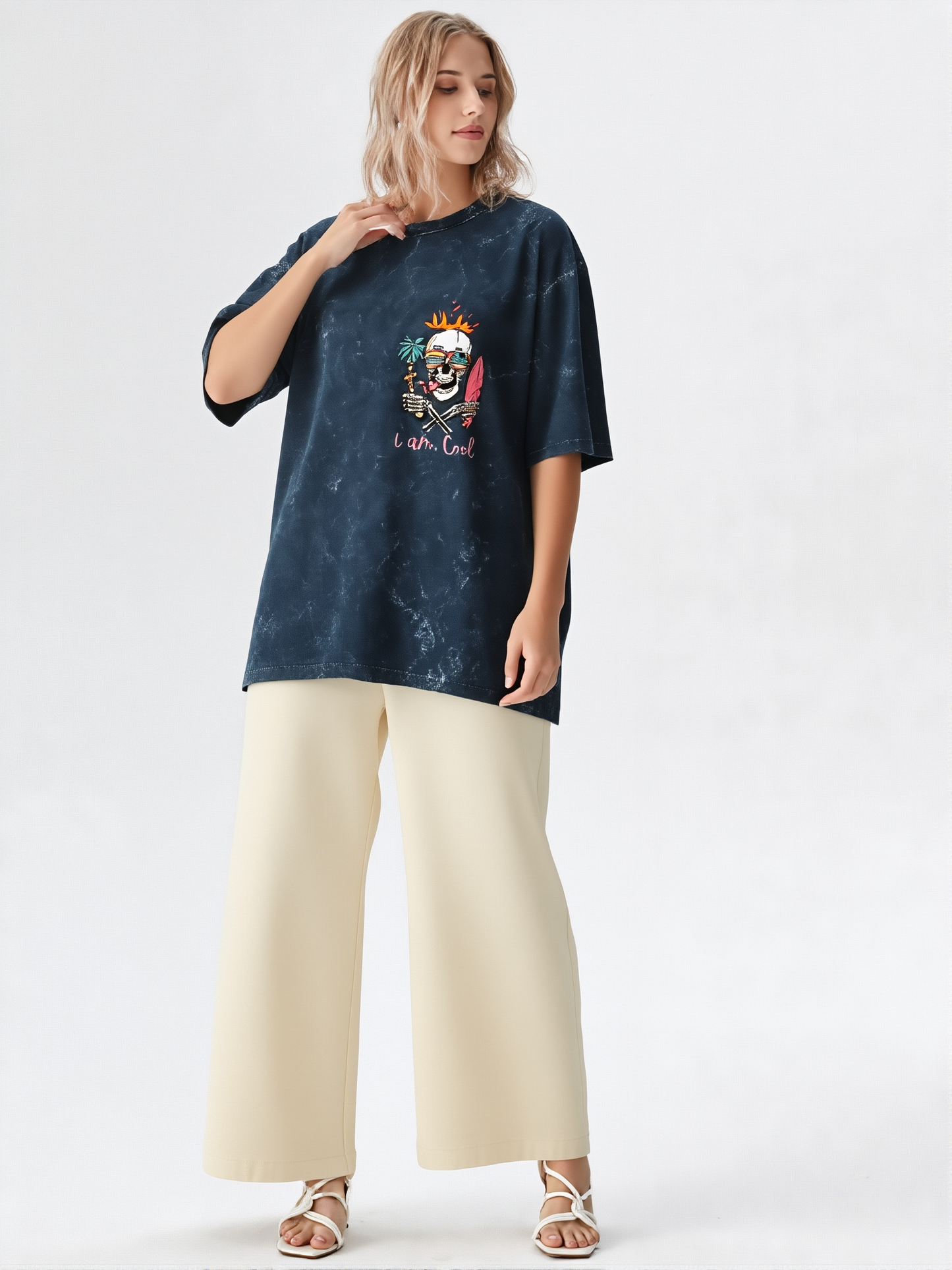 Woman wearing a navy blue t-shirt with a colorful graphic and beige pants on a white background