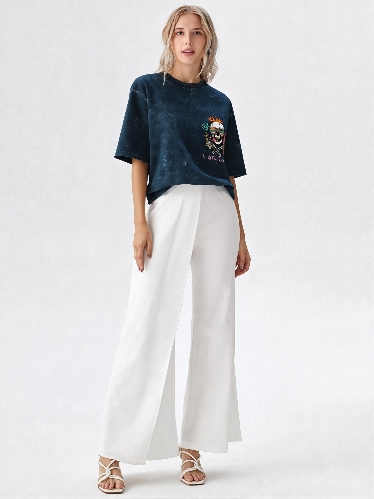 Woman wearing a dark blue t-shirt with a colorful design and white pants on a white background